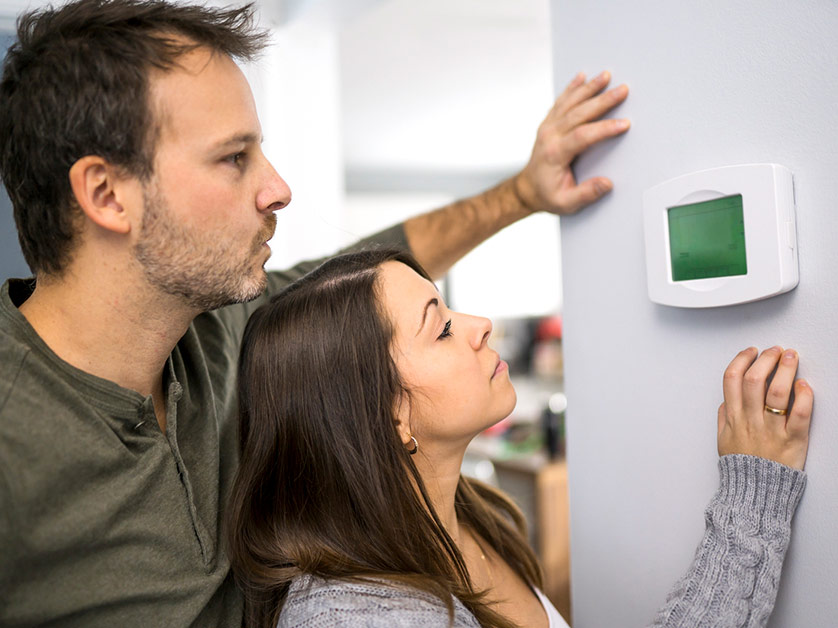 Two people looking at thermostat Two people looking at thermostat
